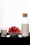 A bottle of milk, a plate of strawberries, a glass of milk on a black cloth on a white background