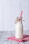Bottle of milk with red straw, wooden background