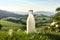Bottle of milk standing on an Alpine meadow with green grass on a sunny summer day. Blue sky mountains in the background