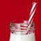 Bottle of Milk with Straw over Red Background