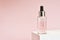 Bottle of moisturizing face oil on a white stand on a pink background. A professional product for a perfect complexion. Women`s ac