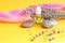 A bottle of natural aromatic oil with sea stones, lavender branches and a light scarf on a yellow background, side view