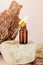 A bottle of natural essential oil on a stone, next to a tree bark with a beautiful texture.