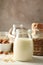 Bottle of oat milk, basket with a glasses of different types milk on wooden background