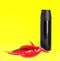 Bottle of pepper spray and red hot chilies on yellow background