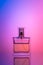 Bottle of perfume on purple neon background. Transparent silhouette, illuminated effect. Toilet water for women. Copy space for
