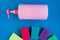 Bottle with pink dishwashing liquid and multicolor sponges on blue background.