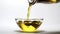 Bottle pouring virgin olive oil in a bowl close up on white background