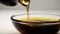 Bottle pouring virgin olive oil in a bowl close up on white background