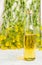 Bottle of rapeseed oil on white wooden table over fresh flowers