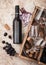 Bottle of red wine and empty glass with dark grapes with corks and opener inside vintage wooden box on wooden background with