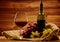 Bottle of red wine, glass and grape in basket in wooden interior