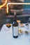 Bottle of red wine and glass on the table, chips, olives, served at restaurant. Soft colours, Summer time, Italy. Copy Space For