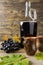 A bottle of red wine near grapes and ceramic mugs on wooden rustic background