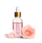 Bottle of rose essential oil and flower on white