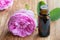 A bottle of rose essential oil with rose flowers in the background