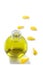 A bottle of rose essential oil with yellow rose petals on a white background