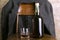 Bottle of rum and old-fashioned glass on the retro wooden chair, male coat on it