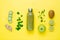 Bottle with smoothie near fruits, vegetables and microgreen ingredients on yellow background