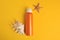 Bottle of sunscreen, starfish and seashell on yellow background, flat lay