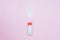 Bottle of Talcum baby powder on pink background. Powder spilled from white container, top view flatlay