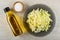 Bottle of vegetable oil  salt in bowl  chopped cabbage in plate on wooden table. Top view