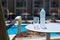 Bottle of water and glass on table at the terrace in hotel against waterpool