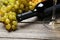 Bottle of white wine with grapes on the grey wooden background