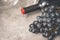 Bottle of wine,  bunch of dark grapes,  empty glass on a gray background  closeup