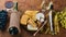 A bottle of wine, and a large assortment of cheeses, honey, nuts and spices, on a wooden table. Top view.