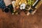 A bottle of wine, and a large assortment of cheeses, honey, nuts and spices, on a wooden table. Top view.