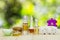 Bottles of aromatic oils with candles, pink orchid, stones and white towel on wooden floor on blurred green bokeh background