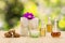 Bottles of aromatic oils with pink orchid, stones and white towel on vintage wooden floor on blurred green bokeh background
