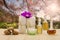 Bottles of aromatic oils with pink orchid, stones and white towel on vintage wooden floor on blurred lake and forest background