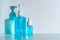 Bottles of blue anti-septic alcohol hand gel and spray on white table and casting blue shadow on white wall background