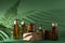 Bottles for cosmetics and cream on a pedestal, green background with leaves and shadow. Brown glass jars with wooden