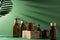 Bottles for cosmetics and cream on a pedestal, green background with leaves and shadow. Brown glass jars with wooden