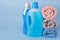 Bottles of detergent and fabric softener with clean towels on blue background. Containers of cleaning products, household