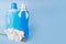 Bottles of detergent and fabric softener with orchid flowers on blue background. Containers of cleaning products, household