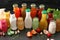 Bottles with different tasty sauces and vegetables on dark table