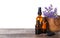 Bottles of essential oil and bowl  lavender flowers on wooden table against white background