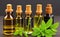 bottles of hemp oil with fresh green leaves on grey background, closeup