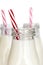 Bottles of Milk with Red Striped Straws over White