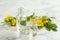 Bottles of natural celandine oil near flowers on white marble table