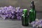 Bottles with natural lavender oil and flowers on wooden table against grey background. Space for text