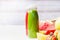 Bottles with smoothies and juices beverages on white table background with summer fruits and berries, front view. Healthy food