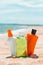 Bottles of sun protection lotion, aloe soothing gel from sun burn, seashells in sand on the beach with sparkling sea in