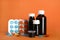 Bottles of syrup, measuring cup and cough drops on orange background