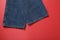 The bottom edge of the trousers of dark blue jeans on a red background