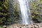 The bottom portion of Waimoku Falls plummeting over volcanic rock covered in moss and into a rock pile in Maui, Hawaii